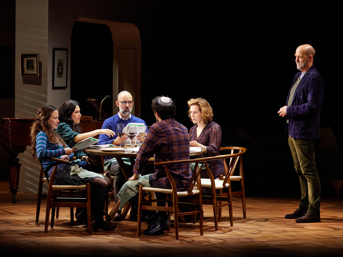 a group sitting around a table with one man standing